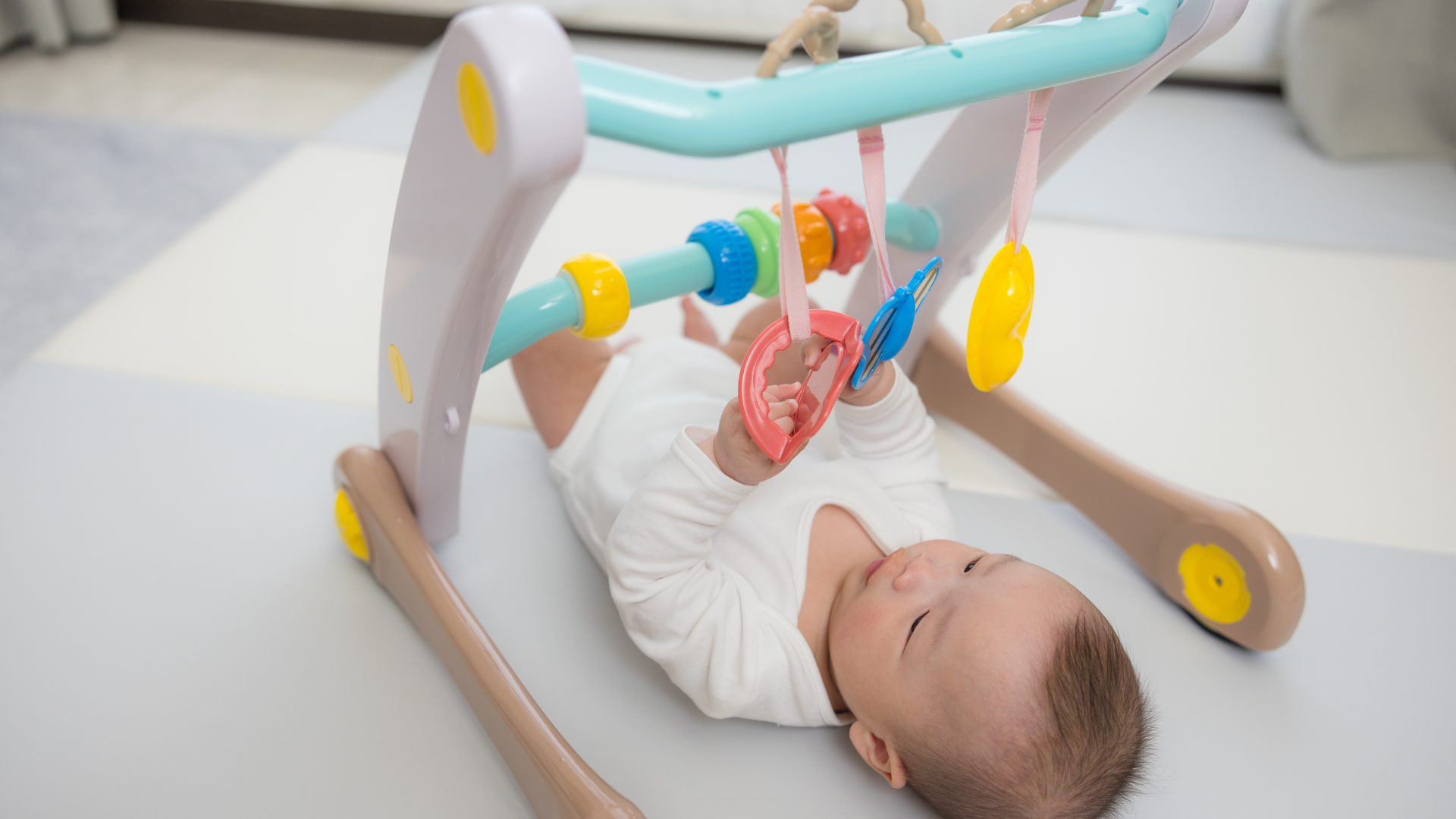 Bagaimana Cara Memilih Baby Gym Apa Itu Baby Gym? Baby gym dilakukan pada enam bulan pertama kehidupan mereka karena bayi berkembang sangat cepat. Memberikan mainan dan melakukan beberapa aktivitas dapat membantu mereka untuk bereksplorasi dengan kemampuan barunya. Pada awalnya si Kecil mudah fokus pada benda yang dekat dengan dirinya, namun akhirnya mereka lebih fokus dengan mainan warna-warni yang ada di sekeliling mereka. Seiring berjalannya waktu, pertumbuhan si Kecil bukan hanya dengan melihat, tetapi juga mulai mencoba meraih sesuatu hingga menepuk mainan. Kondisi ini melatih koordinasi antara tangan dan mata mereka. Baby gym adalah media yang tepat untuk mendukung stimulasi tersebut, karena dilengkapi mainan yang bisa diraih dan disentuh si Kecil. Ketika si Kecil sudah bisa meraih dan menyentuh benda mereka mulai merasa punya kendali atas tubuhnya sendiri. Dari sini si Kecil belajar bahwa tindakannya sangat berpengaruh dengan lingkungan sekitar. Mengapa Baby Gym Penting untuk Bayi? Melakukan baby gym bukan hanya sekedar matras dengan mainan yang digantung di atas. Baby gym dilakukan agar si Kecil mendapatkan ruang bermain yang membantu si Kecil untuk tumbuh, belajar, hingga bersenang-senang. Baby gym perlu dilakukan agar si Kecil mendapatkan keterampilan yang penting untuk pertumbuhannya. Manfaat Baby Gym untuk Tumbuh Kembang si Kecil Pada tahun pertama kehidupan si Kecil mereka cenderung ingin dipeluk dan digendong. Namun, seiring bertambahnya usia mereka cenderung membutuhkan waktu lebih banyak dalam stimulasinya, sehingga hal ini untuk mendukung tumbuh kembang si Kecil. Maka dari itu baby gym bisa menjadi solusi yang bermanfaat bagi si Kecil, ketahui manfaatnya di bawah ini: 1. Mendorong Kebebasan dalam Bergerak Seiring berjalannya usia si Kecil semakin lebih aktif, maka dari itu mereka disarankan untuk melakukan play gym. Ruangan playgym menciptakan ruang aman untuk mereka menendang, berguling, hingga merangkak. Sehingga aktivitas ini dilakukan sebagai olahraga bayi yang membantu memperkuat ototnya. Play gym juga dapat memberikan kesempatan untuk si Kecil dalam mengeksplor secara mandiri. Hal ini penting dilakukan agar si Kecil tumbuh dengan rasa percaya diri dan mandiri sejak dini. Baby gym adalah pilihan tepat untuk mendukung eksplorasi tersebut karena dirancang dengan mainan yang aman sekaligus menstimulasi perkembangan bayi. Artikel lainnya: 7 Manfaat Tummy Time untuk Perkembangan Bayi Sejak Dini 2. Meningkatkan Perkembangan Kognitif Baby gym bukan hanya melatih tubuh si Kecil namun, otak mereka juga dilatih. Sehingga dari sini si Kecil dapat memahami sebab dan akibat, kegiatan yang terjadi seperti saat anak menarik mainan maka akan keluar bunyi. Kemudian bayi juga dapat belajar untuk mengenal warna, bentuk, suara hingga pola yang penting untuk perkembangan intelektual mereka. Interaksi orang tua selama baby gym juga menjadi stimulasi sarana bahasa mereka. 3. Memberi Pengalihan Menarik dalam Rutinitasnya Seiring berjalannya waktu si Kecil membutuhkan aktivitas baru untuk menyalurkan energinya. Baby gym bisa menjadi solusinya karena si Kecil bukan hanya terhibur tapi juga melatih perkembangan tubuh serta otaknya. Maka dari itu di fase ini Mom disarankan untuk komunikasi dengan si Kecil, kegiatan yang dapat dilakukan seperti menunjukan mainan, memperdengarkan suara hingga ngobrol. Interaksi yang dilakukan Mom dan si Kecil dapat memperkuat ikatan emosional dan mendukung kemampuan berbahasa si Kecil. 4. Meningkatkan Koordinasi Tangan, Mata dan Motorik Pada tahun pertama kehidupan mereka si Kecil belajar banyak hal baru, maka dari itu Mom dapat ajari si Kecil baby gym. Baby gym dapat dilakukan di rumah dengan menggunakan mainan gantung, mainan bunyi, hingga mainan dengan objek warna-warni. Pada awalnya si Kecil hanya mengamati mainan yang digantung, namun lama-kelamaan mereka mencoba untuk meraih, menggenggam, menendang hingga menepuk mainannya. Aktivitas ini dapat melatih motorik kasar, halus dan koordinasi antara tangan dan mata. 5. Merancang Panca Indera Play gym dibuat dengan warna yang kontras, pola yang menarik, mainan yang disertai suara, dan memiliki tekstur yang berbeda. Semua ini penting untuk bayi karena pola hitam-putih atau warna cerah dapat menarik perhatian si Kecil yang sedang belajar fokus. Suara yang ada di mainan juga dapat mengasah pendengaran mereka. Taktil merupakan kain yang memiliki tekstur lembut, empuk, hingga berlekuk yang dapat memberikan pengalaman baru bagi indra peraba si Kecil. Artikel lainnya: Apakah Bayi Berenang Aman? Ini Hal yang Perlu Mom Ketahui